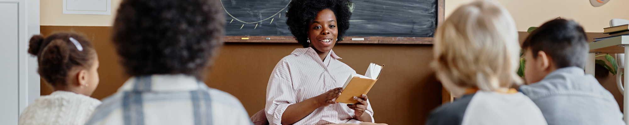 teacher reading a book to young students